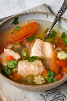 a bowl of fish soup with carrots, celery and coriant