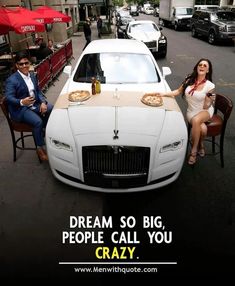 a man and woman sitting in front of a white car