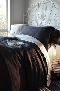 a bed with brown and white linens in a bedroom next to a large window