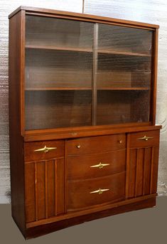 an old wooden china cabinet with glass doors and brass pulls on the bottom shelf,