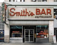 a restaurant called smith's bar on the corner of a city street