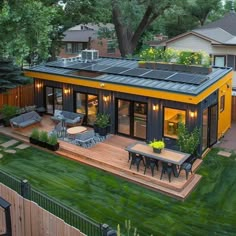 a small house with solar panels on the roof and patio area, surrounded by green grass