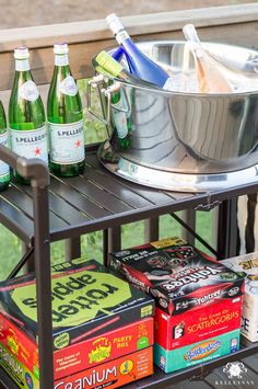 an outdoor bar cart with drinks and snacks on it, along with ice buckets