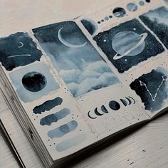 an open notebook with space and clouds on the pages, sitting on top of a wooden table