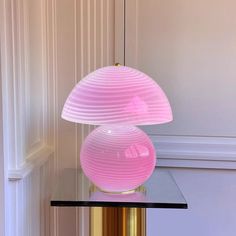 a pink lamp sitting on top of a glass table