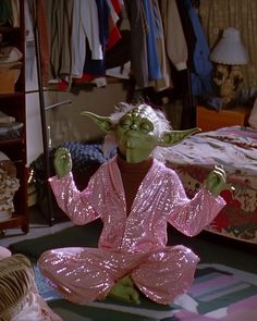 yoda sitting on the floor in pink sequins pajamas and holding two fingers up