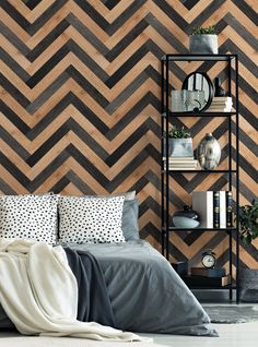 a bed with pillows and blankets in front of a chevron wallpapered pattern