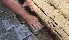 a man is holding something in his hand on the ground next to a brick wall