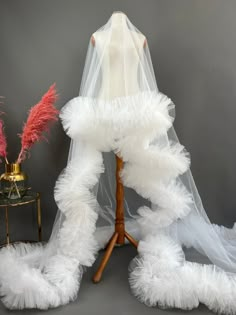 a white veil and some red flowers on a table next to a mannequin