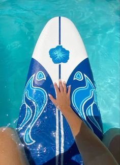 a person holding onto a blue and white surfboard in the water with their hand on it