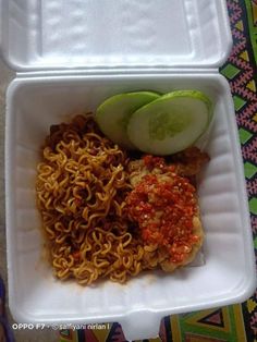 a foam container filled with noodles, meat and cucumber on top of it