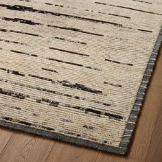 a close up of a rug on a wooden floor with wood floors and white walls