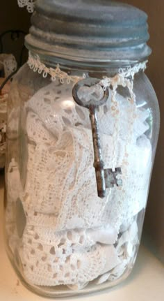 a glass jar filled with lace and a key