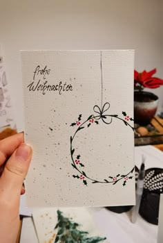 a hand holding up a christmas card with an ornament on it