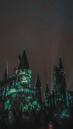 hogwarts castle lit up at night with green lights on it's sides