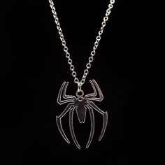 a necklace with a spider on it is hanging from a silver chain that has been placed in front of a black background