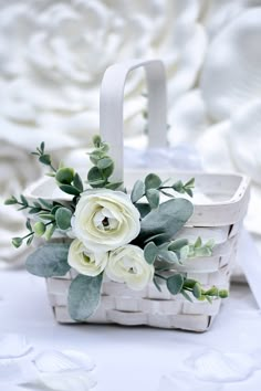 a white basket with flowers and greenery in it