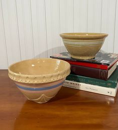 a bowl sitting on top of a wooden table next to two books and a vase