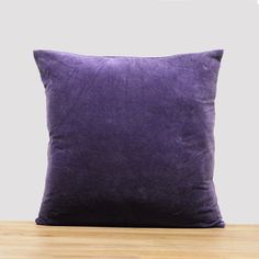 a purple pillow sitting on top of a wooden table