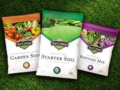 three bags of garden soil sitting on top of a green grass covered field next to each other