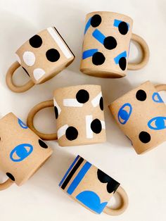 six coffee cups with black and blue designs on them are sitting next to each other