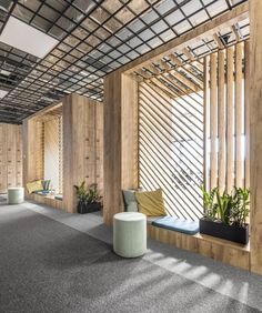 an office with wooden partitions and plants on the wall, in front of large windows