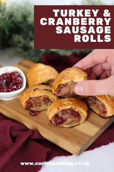 a person pointing at some pastries on a cutting board with cranberry sauce