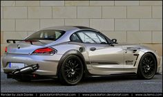 a silver sports car parked in front of a building with its rear end down and the hood up