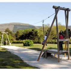 a wooden swing set sitting in the middle of a park