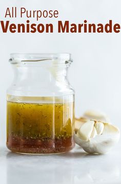 an all purpose venison marinade in a glass jar next to garlic