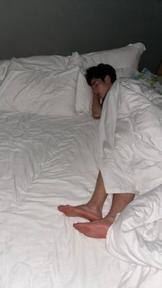 a person laying in bed with white sheets