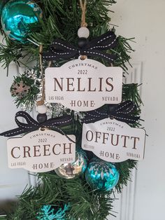 a christmas tree with ornaments hanging from it's branches and name tags on the front door