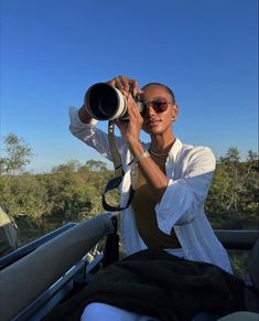 a woman taking a photo with her camera in the back of a truck on a sunny day