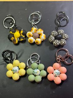 several key chains with different designs on them sitting on top of a black table next to each other