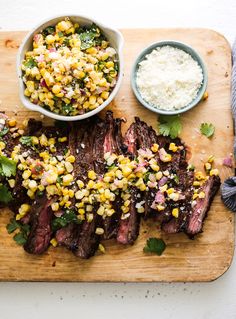 steak with corn on the cob, and two small bowls of mashed potatoes