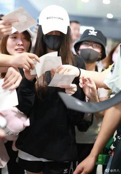 a group of people standing around each other with masks on their faces and paper in front of them