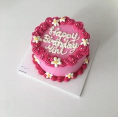 a birthday cake with pink frosting and white flowers