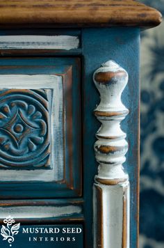 an old blue and white cabinet with ornate carvings on the door knobs is shown