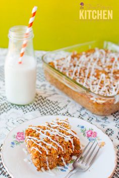 a white plate topped with a piece of cake next to a glass container filled with milk