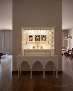 a white shelf with pictures on it in the middle of a wooden floored room