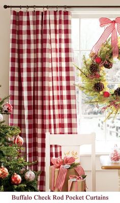 a christmas tree in front of a window with red and white checkered drapes