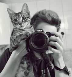 a man holding a camera taking a picture of a cat in front of his face