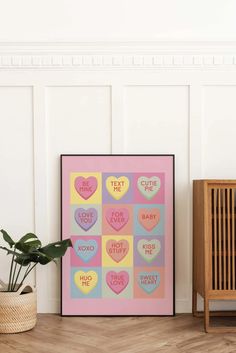 a colorful poster with hearts on it next to a potted plant and wooden chair