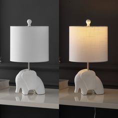 two white elephant lamps sitting on top of a table next to each other and one light is turned on