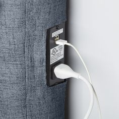 an electronic device plugged into the side of a blue fabric pillow with a white cord