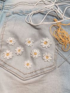 a pair of blue jeans with white daisies on the back and yellow string attached to them