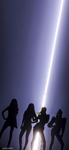 the silhouettes of four people dancing in front of a bright light