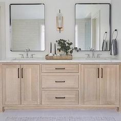 a bathroom with double sinks and two mirrors on the wall next to eachother