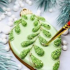 a decorated cookie with green frosting and decorations on it next to christmas tree branches