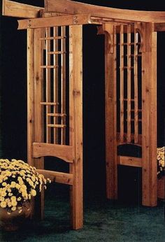 a wooden gazebo sitting on top of a green floor next to a potted plant